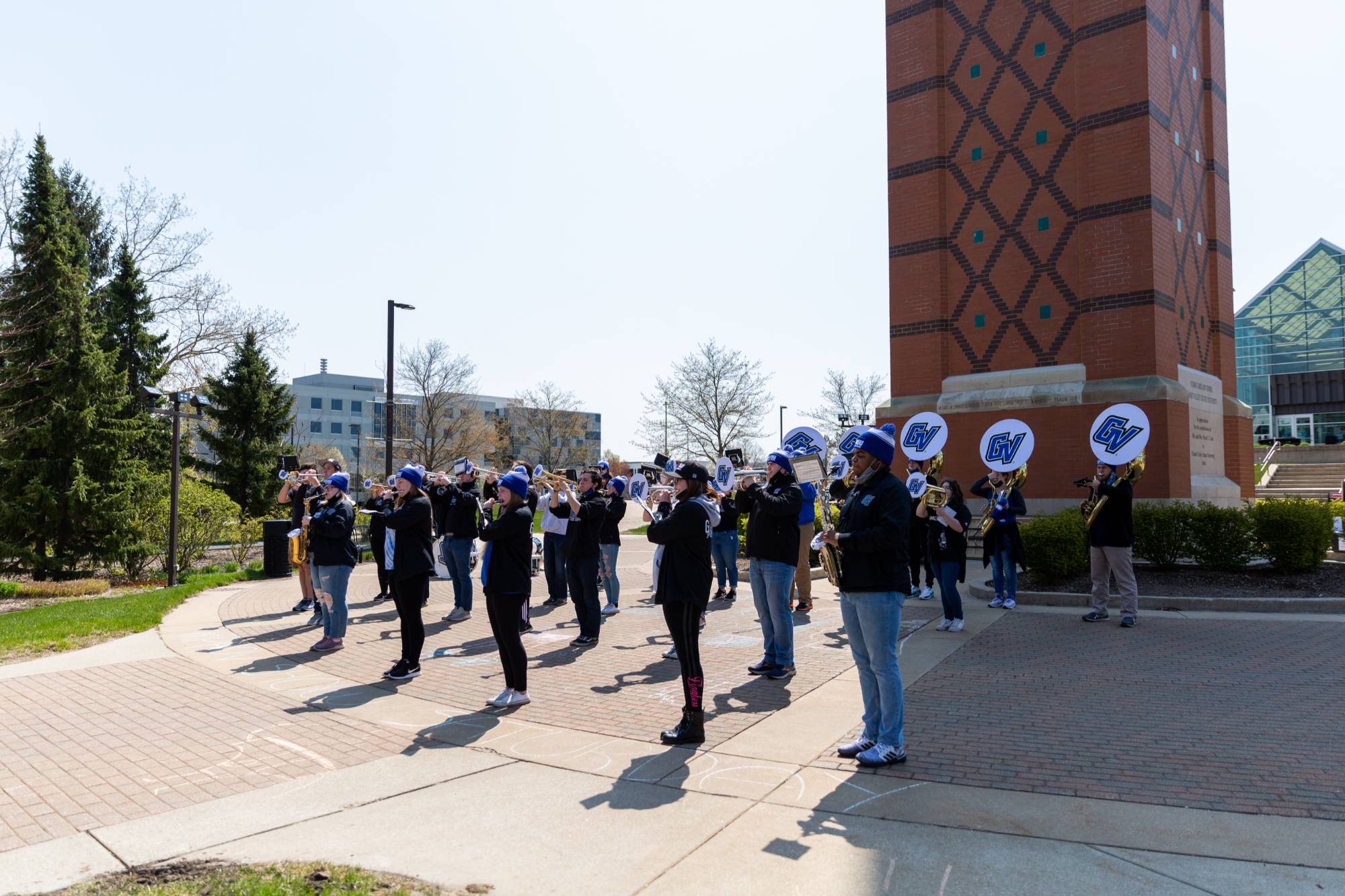 GVSU Marching Band members standing in front of the clock tower playing instruments